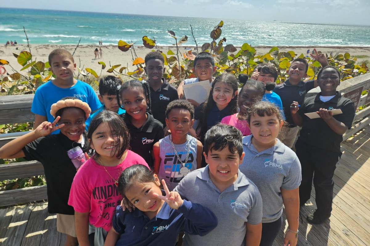 students at PBMA tuition-free charter school pose on a boardwalk near the beach