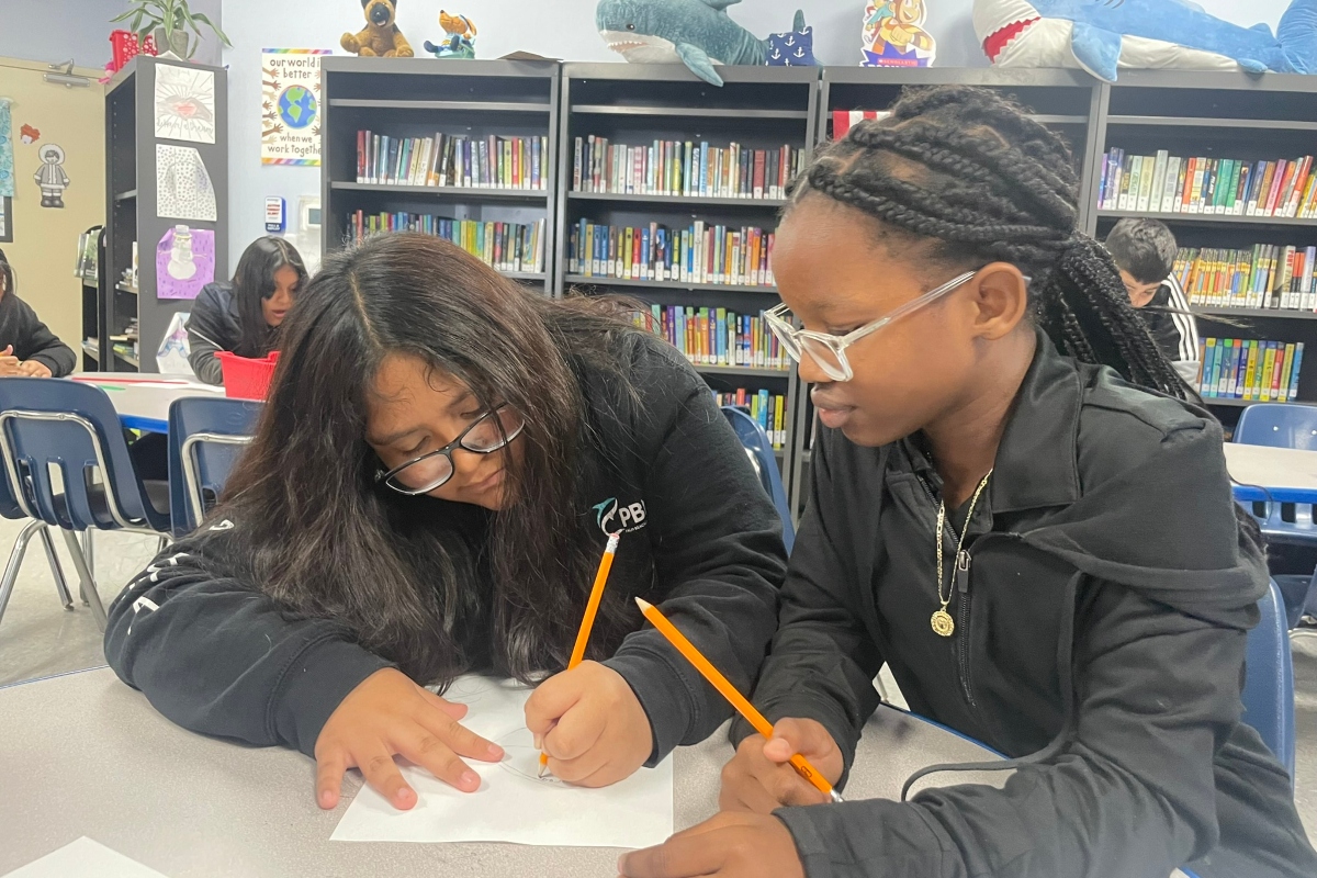 two students working problem solving together at a table in tuition-free charter school PBMA